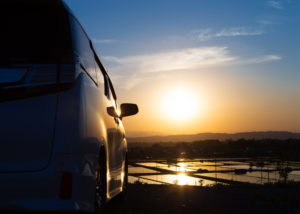 水田に反射しながら沈む夕日と自動車の写真素材