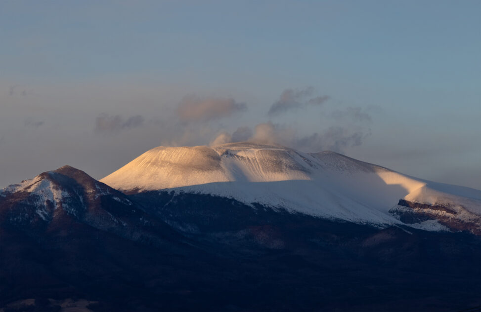 夕日に照らされる雪の浅間山の写真